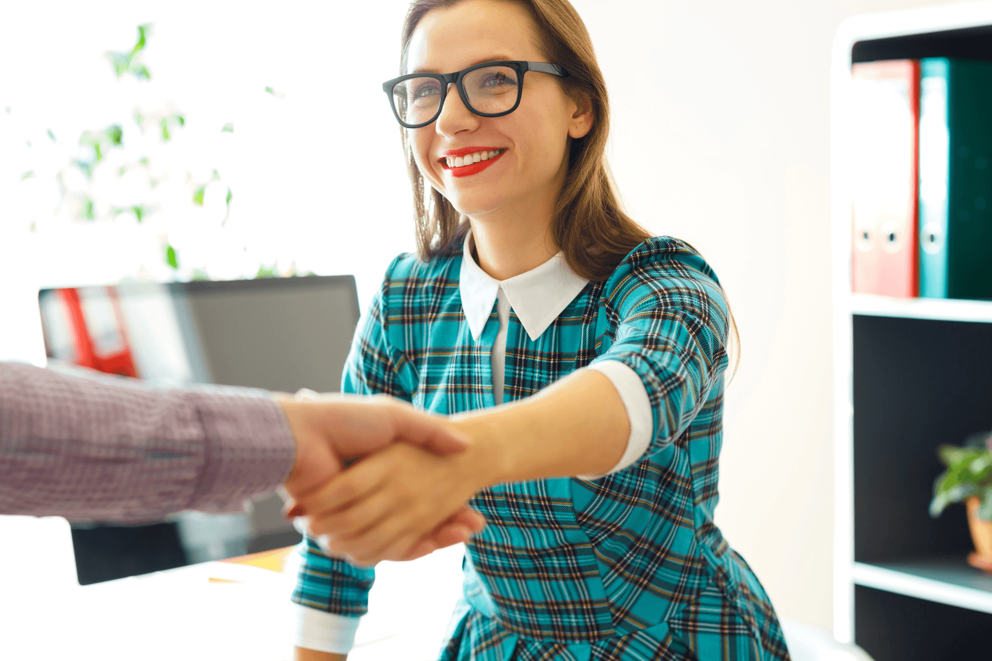 Woman in an office shaking hands with a colleague.
